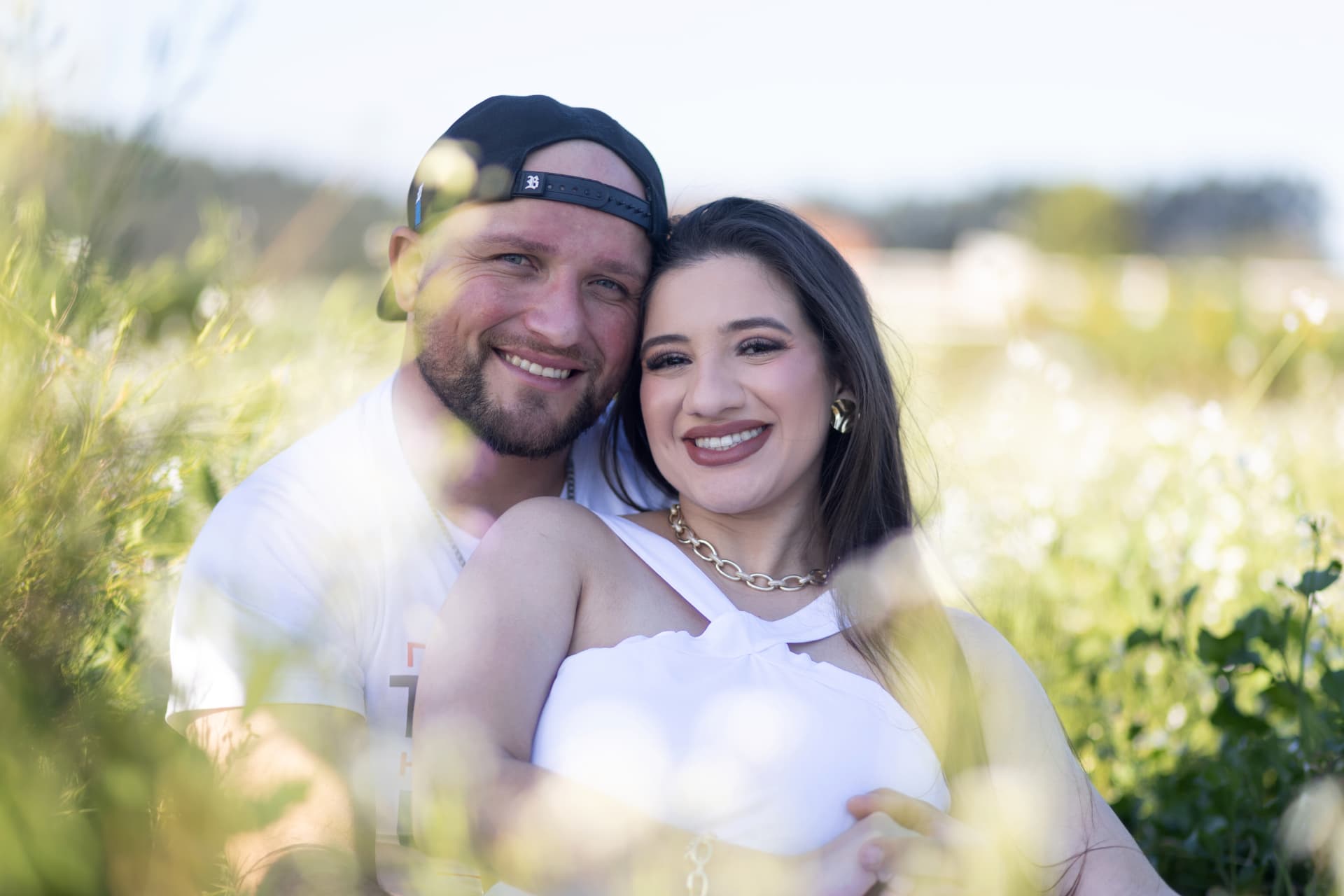 Casal sorrindo em ensaio no campo de flores