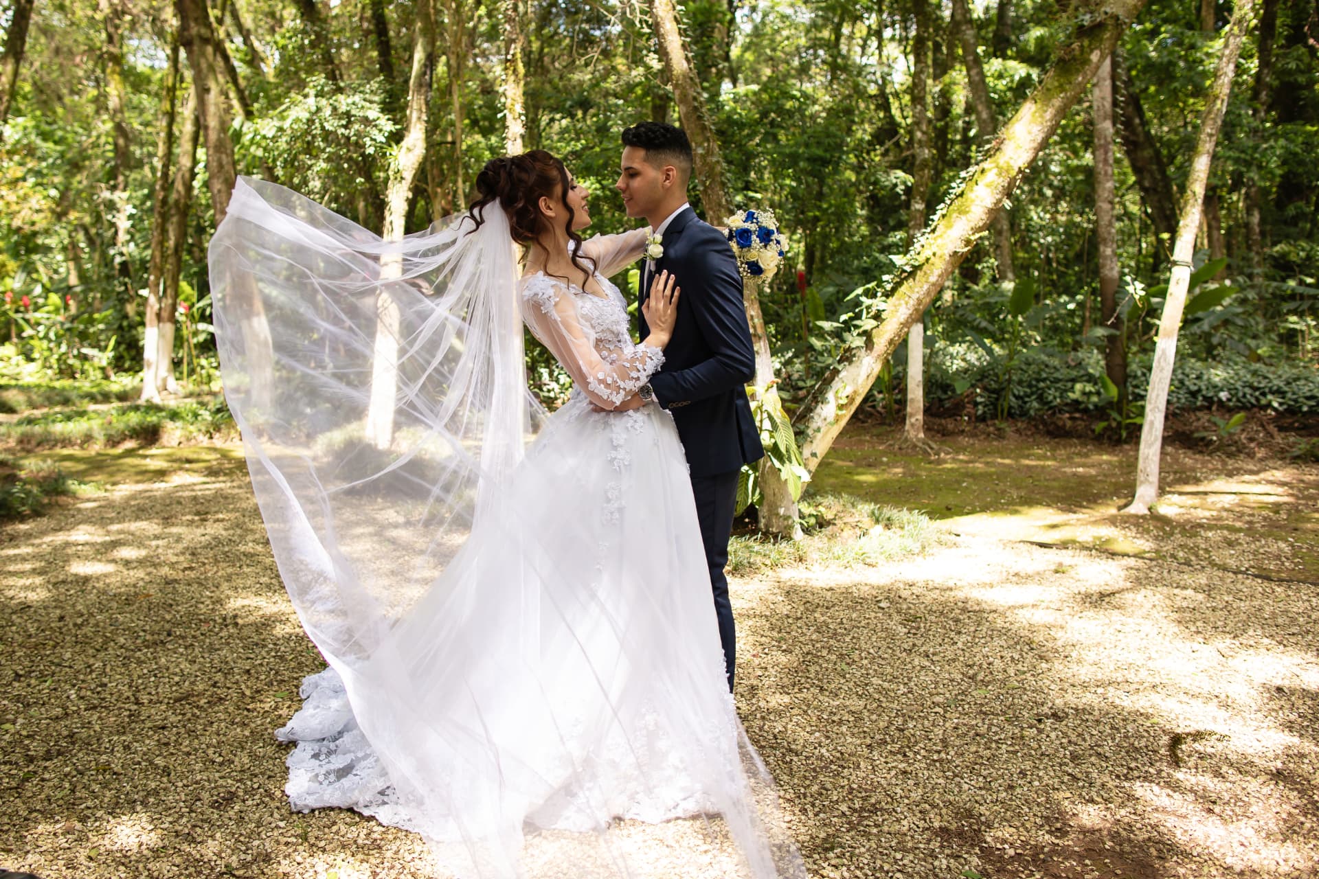 Noiva com véu ao vento durante ensaio de casamento no bosque
